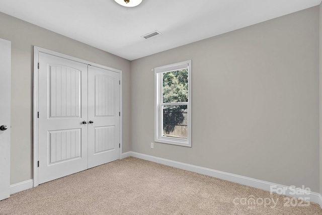 unfurnished bedroom with visible vents, baseboards, light colored carpet, and a closet