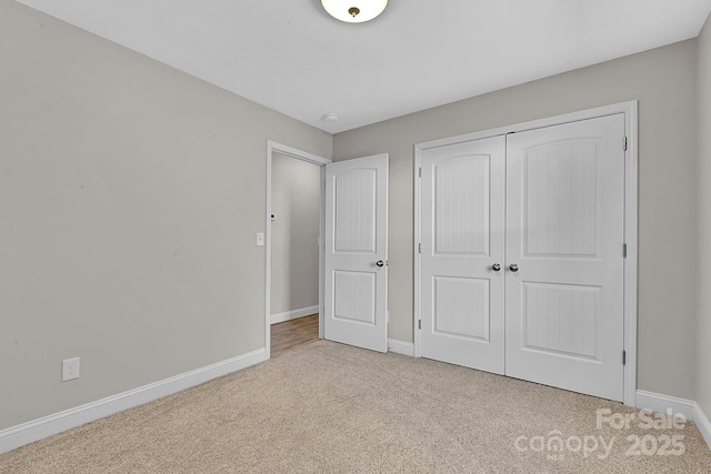 unfurnished bedroom with a closet, carpet flooring, and baseboards