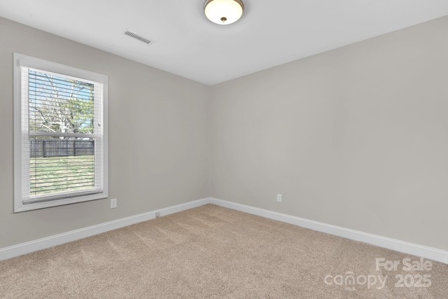 unfurnished room with visible vents, light colored carpet, and baseboards