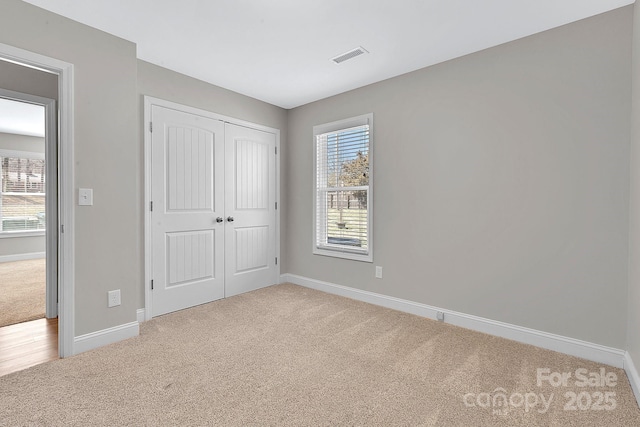 unfurnished bedroom with visible vents, multiple windows, carpet, and baseboards