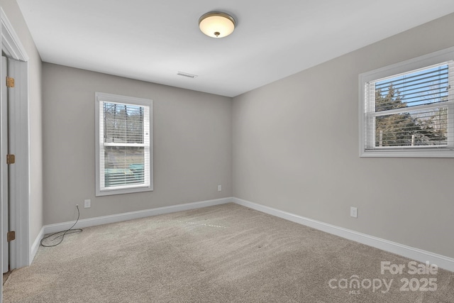 spare room featuring visible vents, carpet, and baseboards