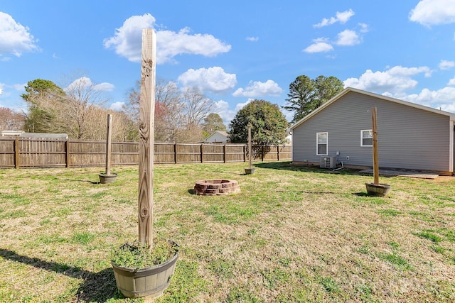 view of yard featuring cooling unit, a fenced backyard, and an outdoor fire pit