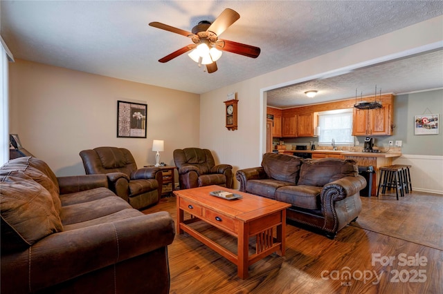 living area featuring ceiling fan, a textured ceiling, and wood finished floors