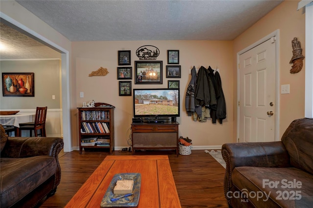 living area featuring dark wood finished floors, baseboards, and a textured ceiling