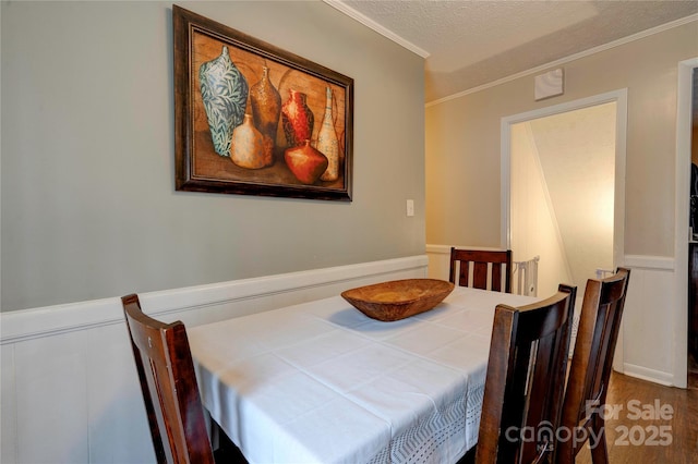 dining space with a textured ceiling, wood finished floors, and crown molding