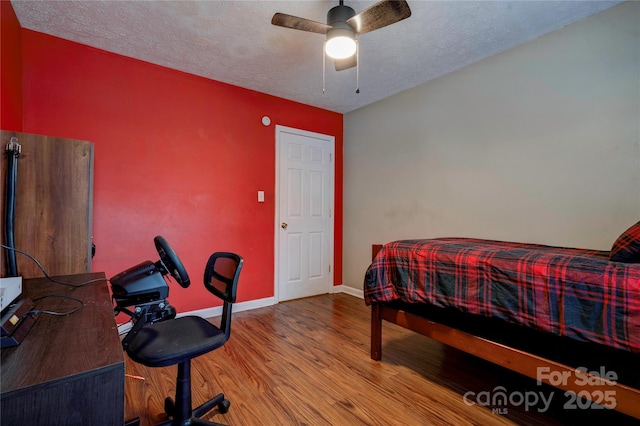 bedroom featuring ceiling fan, a textured ceiling, baseboards, and wood finished floors