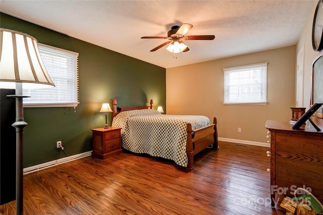 bedroom featuring ceiling fan, a textured ceiling, baseboards, and wood finished floors