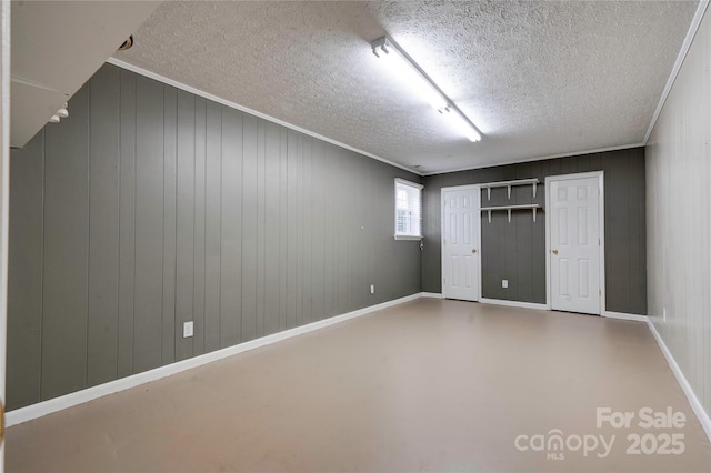 empty room with a textured ceiling, crown molding, baseboards, and finished concrete floors