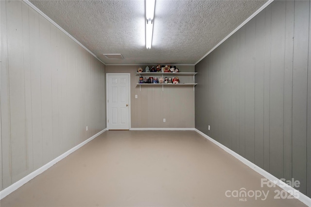 spare room featuring baseboards, a textured ceiling, and ornamental molding