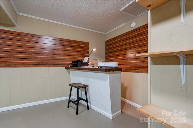 kitchen with a textured ceiling, concrete flooring, and wood walls