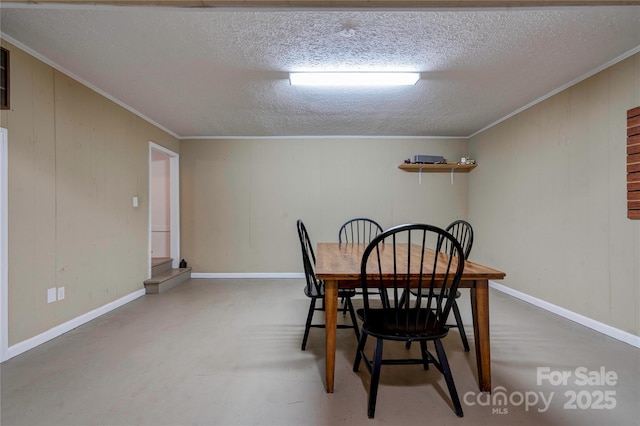 dining area with baseboards, a textured ceiling, ornamental molding, and finished concrete flooring