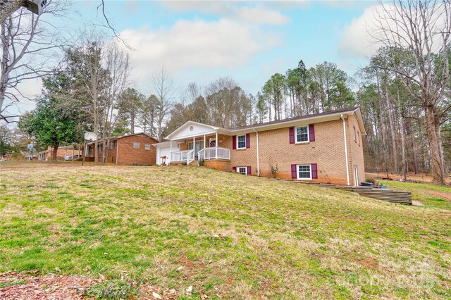 back of house with brick siding, a lawn, and a porch