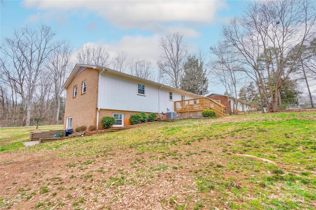 view of side of property with brick siding, central air condition unit, a yard, and a deck