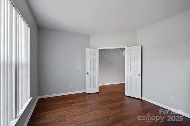 empty room with dark wood-type flooring and baseboards