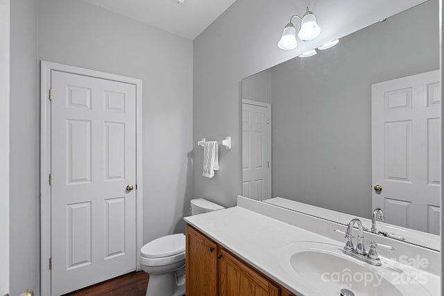 bathroom with vanity, toilet, and wood finished floors