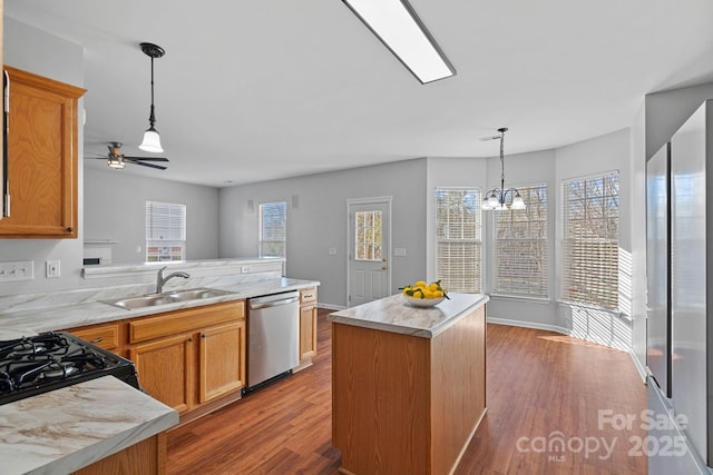 kitchen with dishwasher, a peninsula, wood finished floors, and a sink