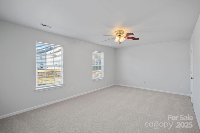 unfurnished room featuring a healthy amount of sunlight, visible vents, light carpet, and baseboards