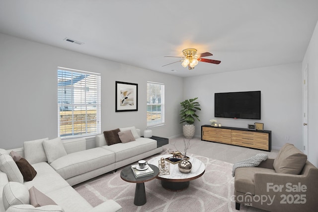 living room with a ceiling fan, light colored carpet, visible vents, and baseboards