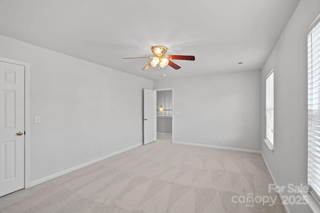 empty room featuring baseboards, a ceiling fan, and light colored carpet