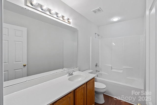 bathroom featuring visible vents, toilet, vanity, shower / tub combination, and wood finished floors