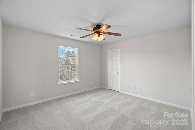 spare room with light carpet, baseboards, visible vents, and a ceiling fan