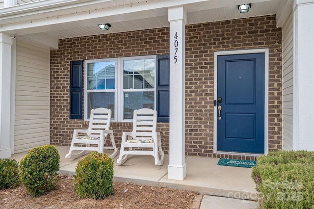 property entrance with covered porch and brick siding