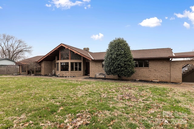 back of property featuring a yard, brick siding, a chimney, and fence