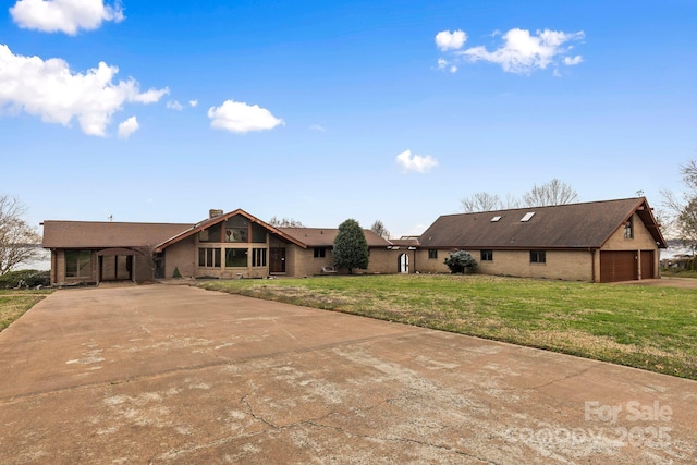 view of front of home featuring brick siding, a front yard, a chimney, and driveway