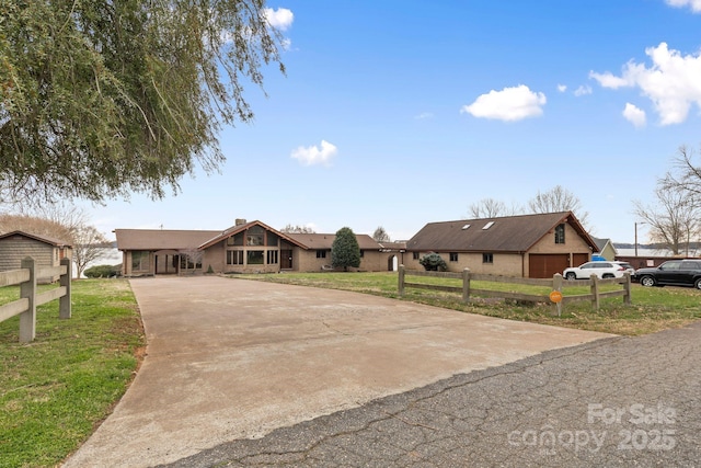 view of front of house featuring concrete driveway, a front lawn, and fence