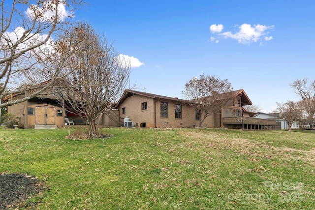 back of house with brick siding, a wooden deck, an outdoor structure, a yard, and crawl space