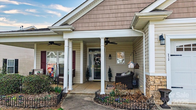 view of exterior entry with stone siding, an attached garage, and a ceiling fan