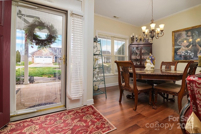 dining space featuring wood finished floors, baseboards, a chandelier, and ornamental molding