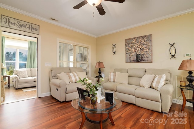 living area with visible vents, a ceiling fan, wood finished floors, and crown molding