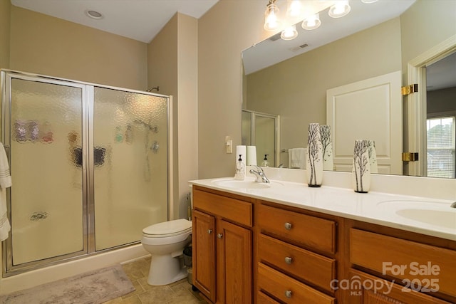 full bath featuring double vanity, a stall shower, toilet, and a sink