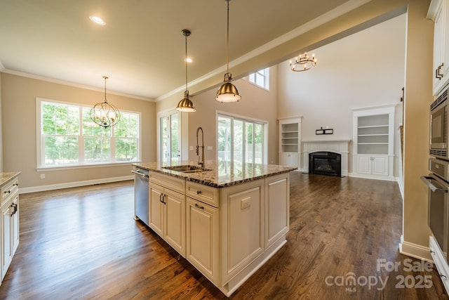 kitchen featuring a glass covered fireplace, dark wood-type flooring, a sink, and a notable chandelier