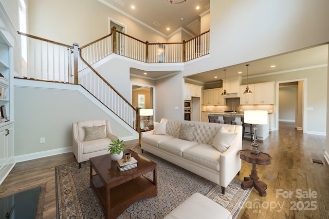 living area with ornamental molding, dark wood-style flooring, and baseboards