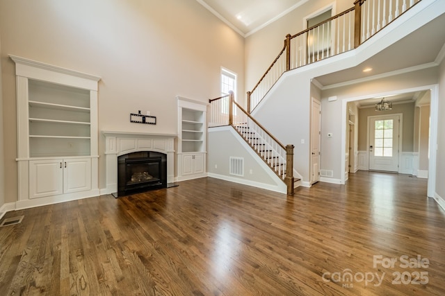 unfurnished living room with a wealth of natural light, visible vents, and wood finished floors