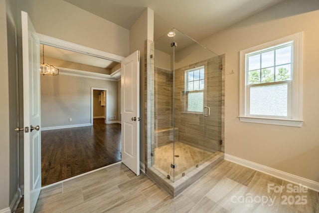 full bath with a stall shower, an inviting chandelier, and baseboards