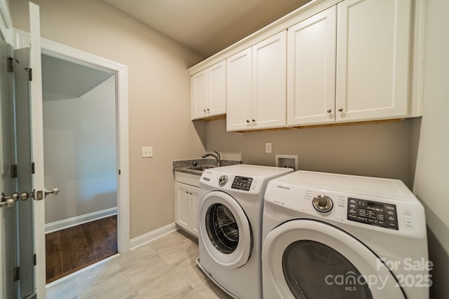 clothes washing area with independent washer and dryer, a sink, cabinet space, and baseboards