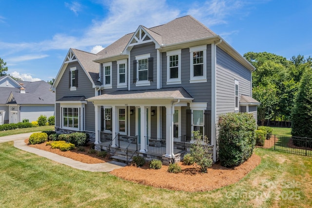 craftsman inspired home featuring a porch, a front yard, fence, and a shingled roof