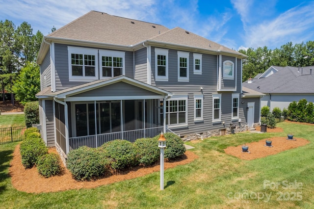 rear view of property featuring a yard, roof with shingles, fence, and a sunroom