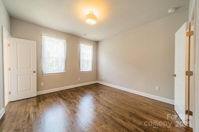 unfurnished bedroom with dark wood-type flooring and baseboards