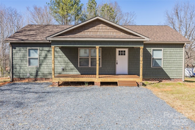 view of front of home with crawl space, covered porch, and roof with shingles