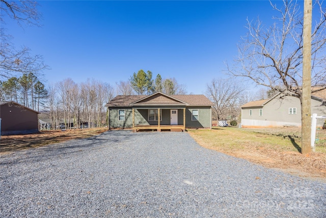 view of front of home with gravel driveway and a porch