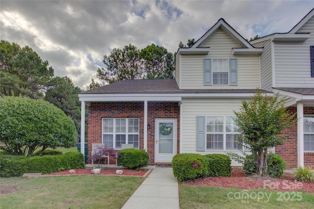 traditional-style house featuring brick siding, a front lawn, and a shingled roof