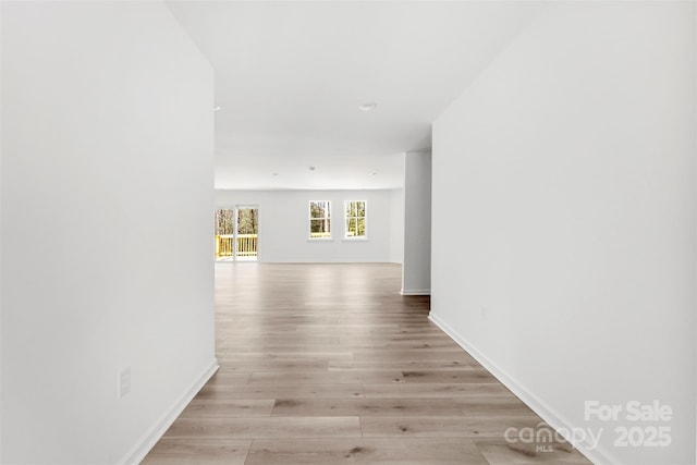 corridor featuring light wood finished floors and baseboards