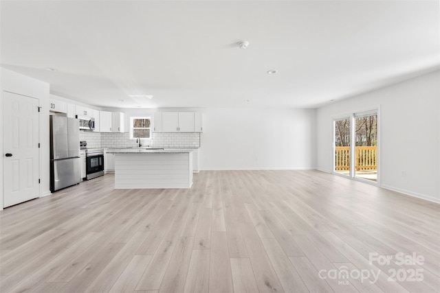 unfurnished living room with baseboards and light wood-style floors