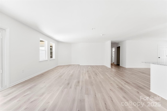 unfurnished room featuring baseboards and light wood finished floors