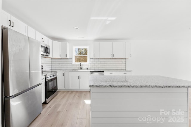 kitchen featuring light stone countertops, light wood-style floors, tasteful backsplash, and stainless steel appliances