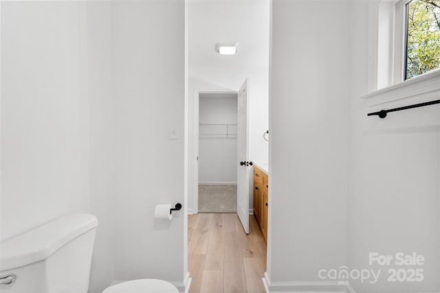 bathroom featuring toilet, baseboards, wood finished floors, and vanity